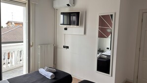Una habitación de hotel con una cama, un televisor, un espejo y un radiador.