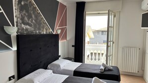 Habitación de hotel con dos camas, un ventanal grande, un radiador y vistas al exterior.