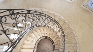 Una escalera metálica curva con diseños intrincados, que conduce a un techo abovedado con paneles decorativos.
