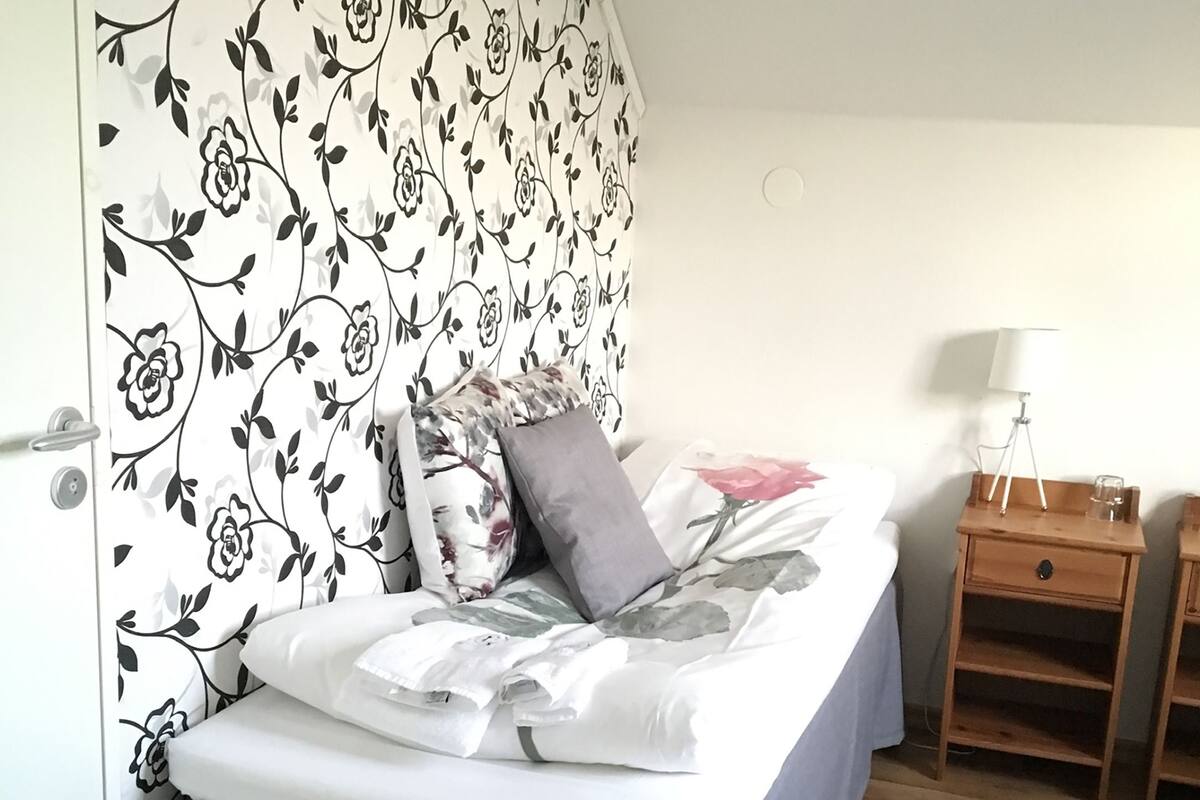 Ein Schlafzimmer mit Bett, Nachttisch, Lampe und Holzboden.