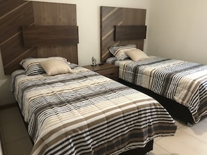 Two single beds with striped bedding and a wooden headboard.