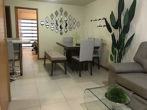 Relax in this stylish living room with a sofa, dining table, and glass coffee table.