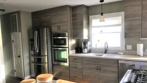 Eine moderne Küche mit Edelstahlgeräten, einem Fenster mit Sternenverzierung und einer Arbeitsfläche mit Schneidebrett und Zitrone.