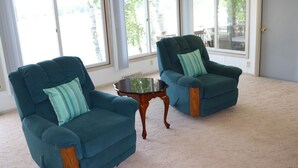 Un salon spacieux avec deux fauteuils turquoise et une table basse en verre.