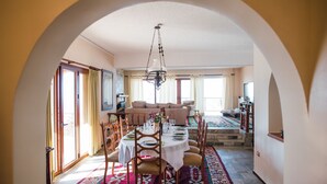 A dining area with a table set for four, a chandelier, and a patterned rug. - Traditional Luxury Villa Armonia (Aigialeia)