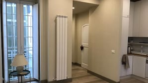 A hallway with a radiator, a table with a lamp, and a kitchen area with cabinets and a countertop. - Dimora Spina in Centro (Campobasso)