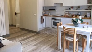 A modern kitchen with white cabinets, a dining table with chairs, and a small rug on the floor. - Dimora Spina in Centro (Campobasso)