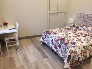 A bedroom with a bed, a desk, and a chair.