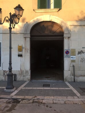 Una entrada a un edificio con un arco, una farola y una señal que indica zona de no estacionamiento.