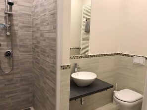 A bathroom with a shower, a sink, and a toilet.