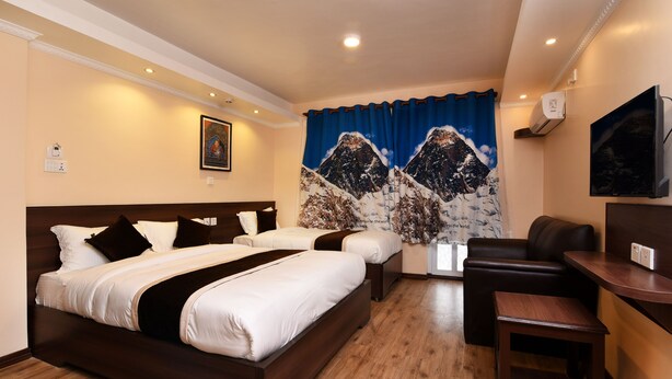 A hotel room with a large bed, a smaller bed, a desk, and a chair. - Hotel Ruza Nepal (Kathmandu)