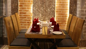 A dining area with a brick wall, wooden table, and chairs. - Hotel Ruza Nepal (Kathmandu)