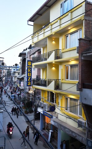 A multi-story hotel with balconies, a visible restaurant, and a street view with pedestrians and vehicles. - Hotel Ruza Nepal (Kathmandu)