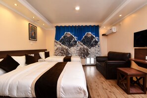 A hotel room with two beds, a sofa, a TV, and a curtain with a mountain design. - Hotel Ruza Nepal (Kathmandu)