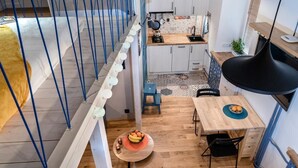 Eine moderne Küche mit Essbereich, Holzboden und einer Treppe mit blauen Geländern.