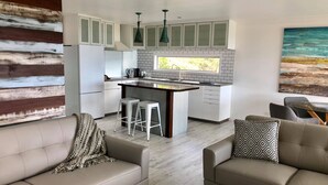 Une cuisine moderne avec des meubles blancs, un îlot central et des luminaires suspendus.
