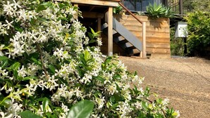 Une maison moderne dotée d’une véranda en verre, d’une terrasse en bois et d’un escalier menant à un deuxième étage.