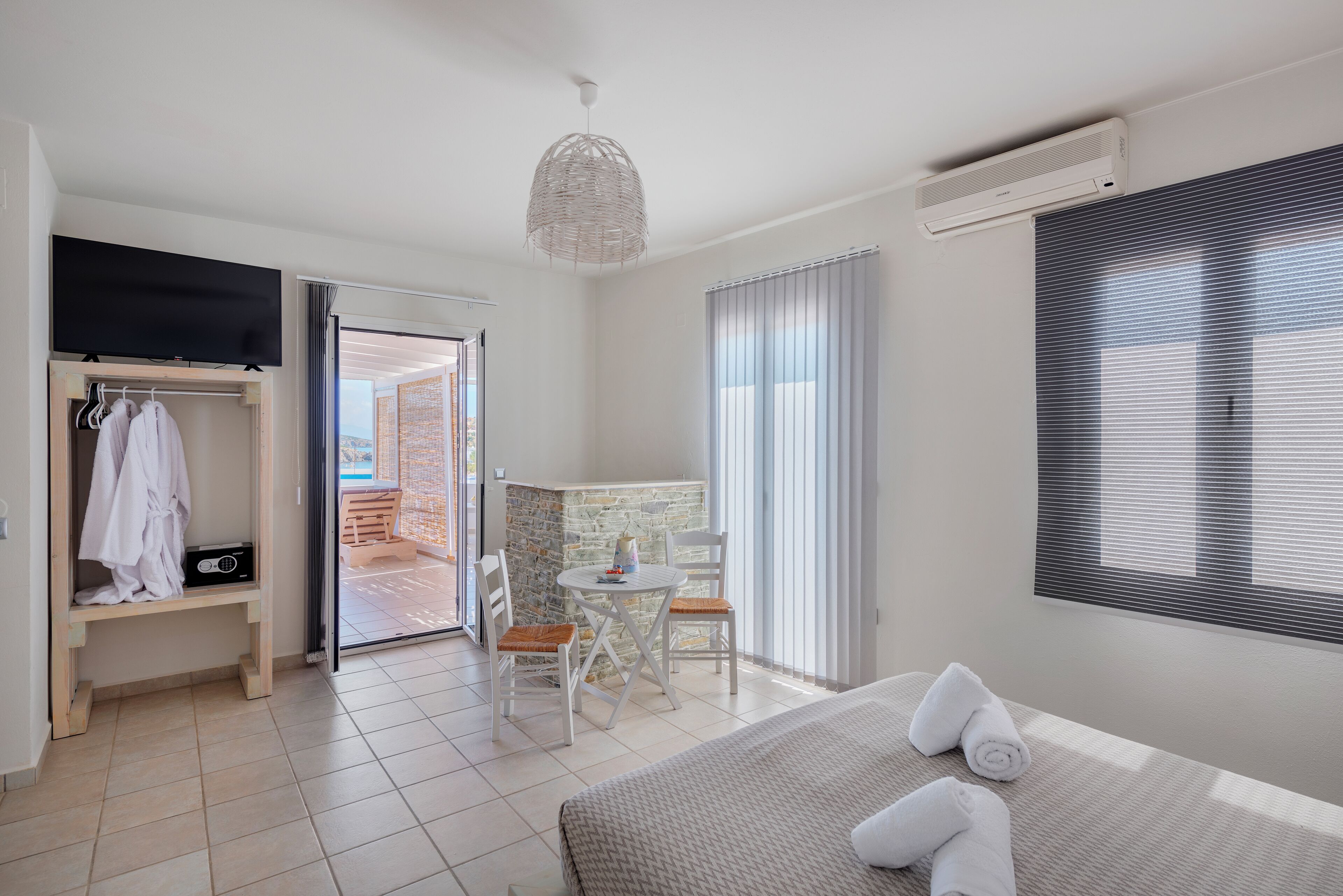 A hotel room with a bed, a desk, a chair, a wardrobe, and a balcony.