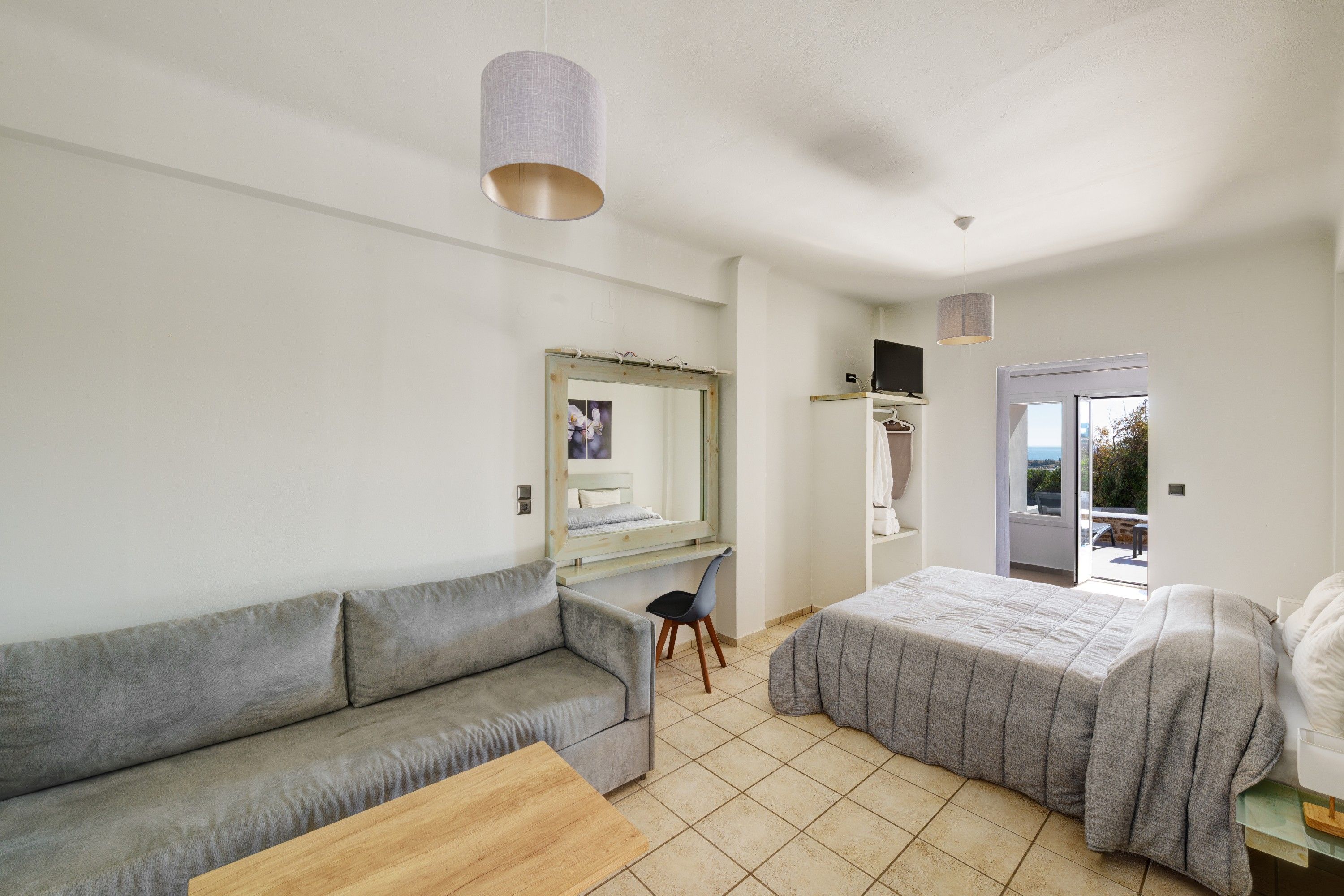 Ein Schlafzimmer mit einem Bett, einem Sofa, einem Schreibtisch und einem Spiegel.