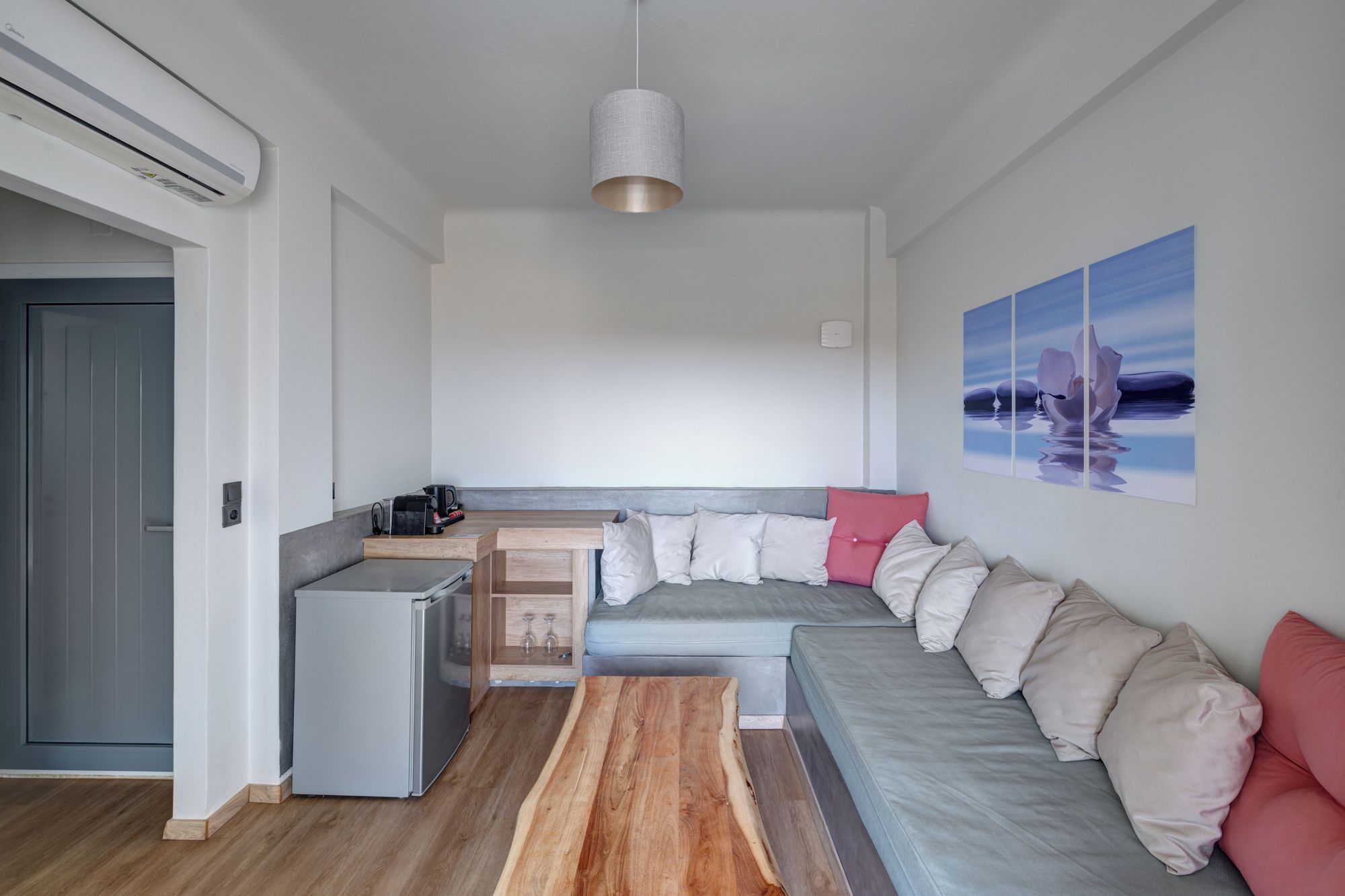 A compact living space with a kitchenette, a dining area, and a sofa with cushions.