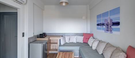 A compact living space with a kitchenette, a dining area, and a sofa with cushions.