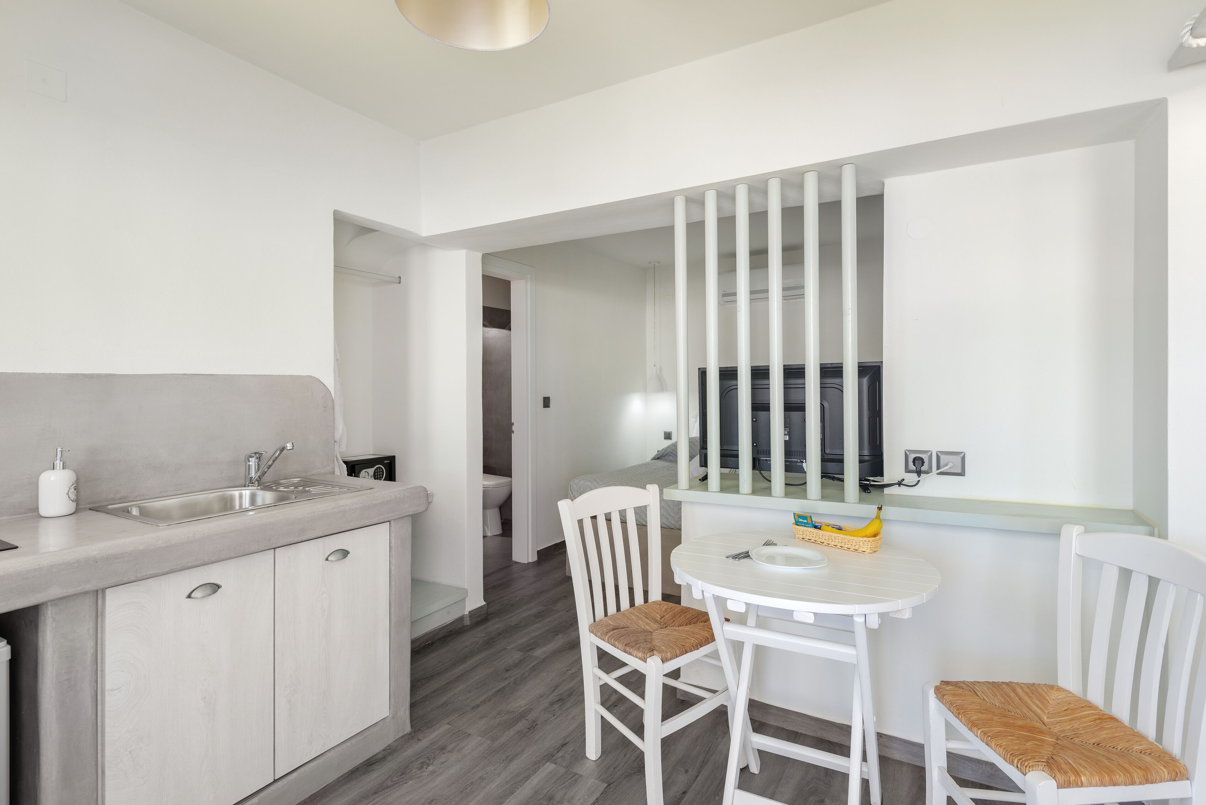 A modern kitchen with a sink, cabinets, and a dining area with a table and chairs.