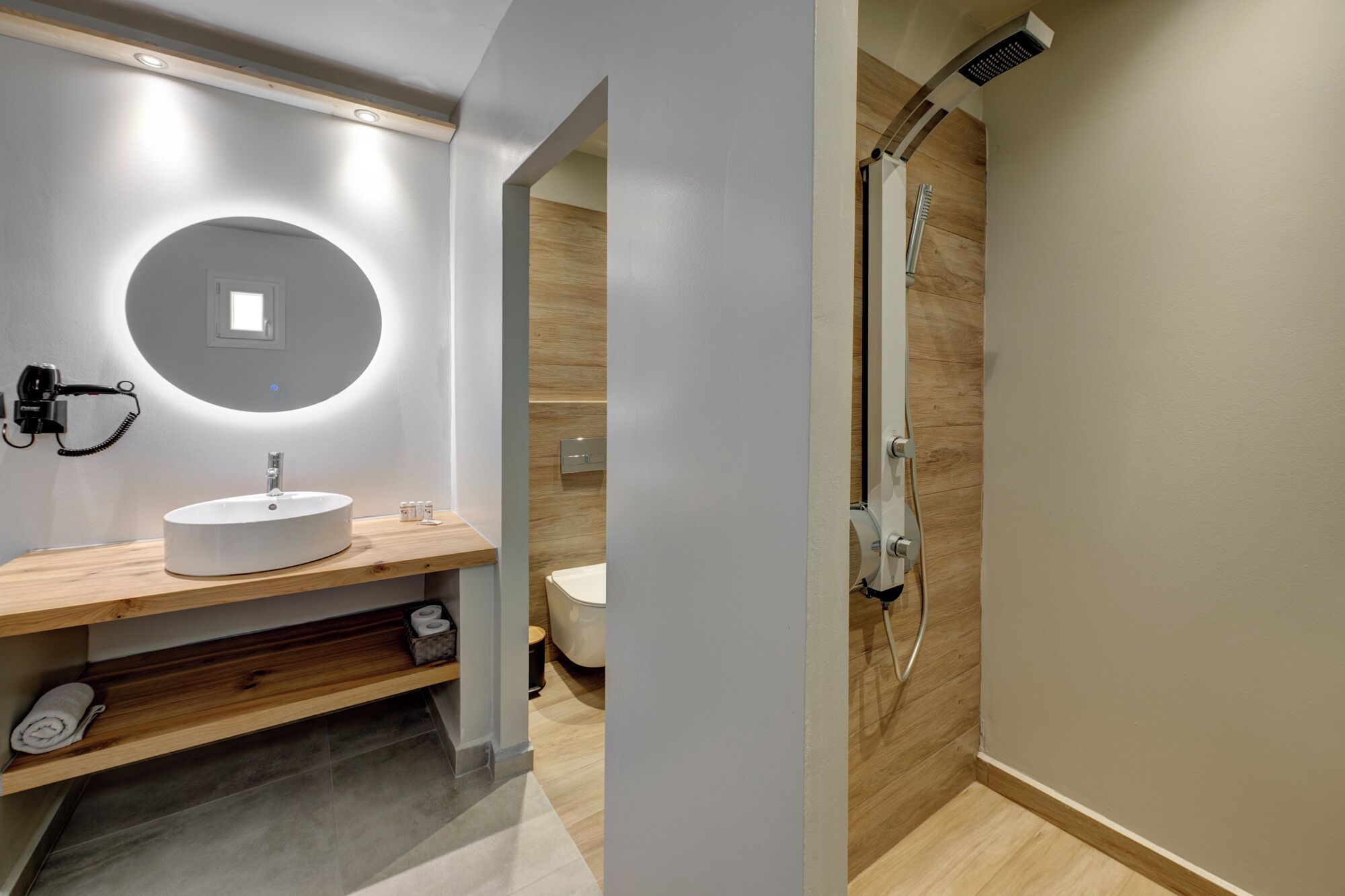 A modern bathroom with a round mirror, a white sink, and a shower.
