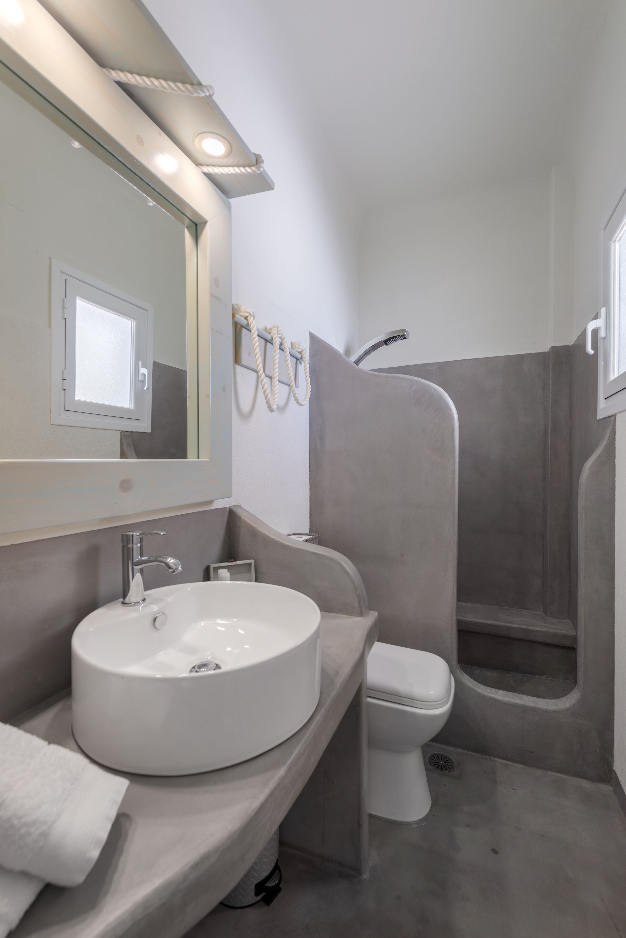 Een moderne badkamer met een rond wastafel, toilet en douchecabine.