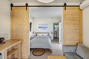 A modern hotel room with a bed, a sofa, a wooden desk, and a dining area. - Aegean Paradiso Vacation Club Adults Only (Syros)