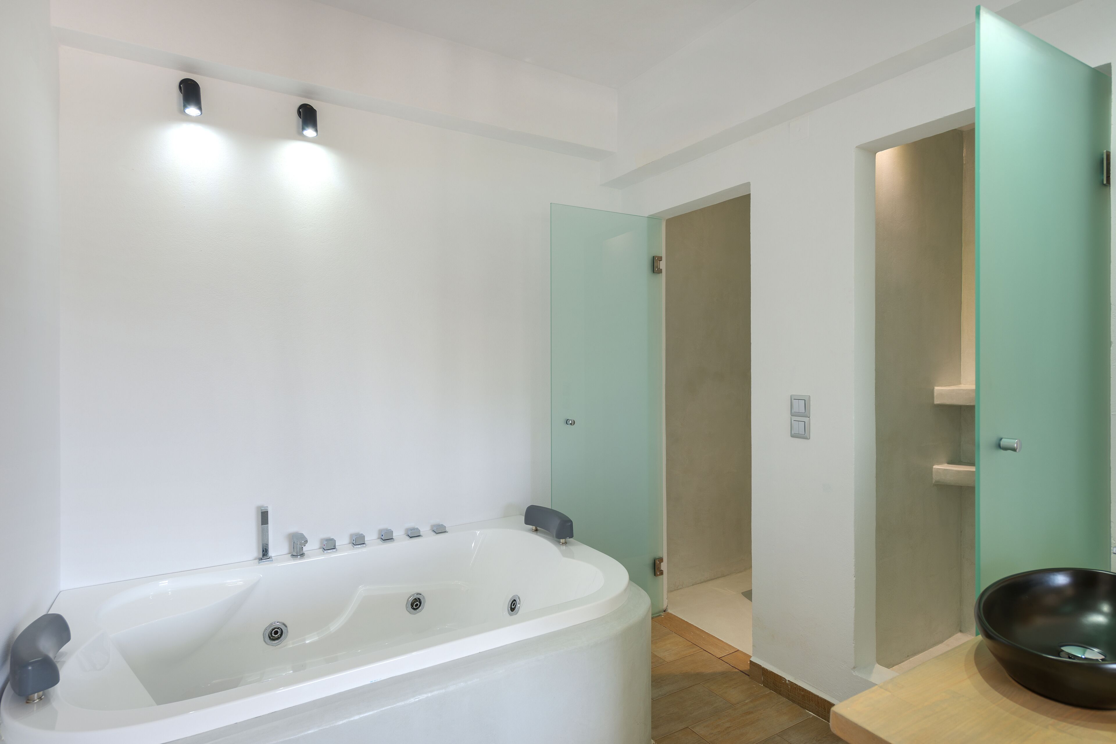 A modern bathroom with a large bathtub, a glass shower enclosure, and a wooden vanity.