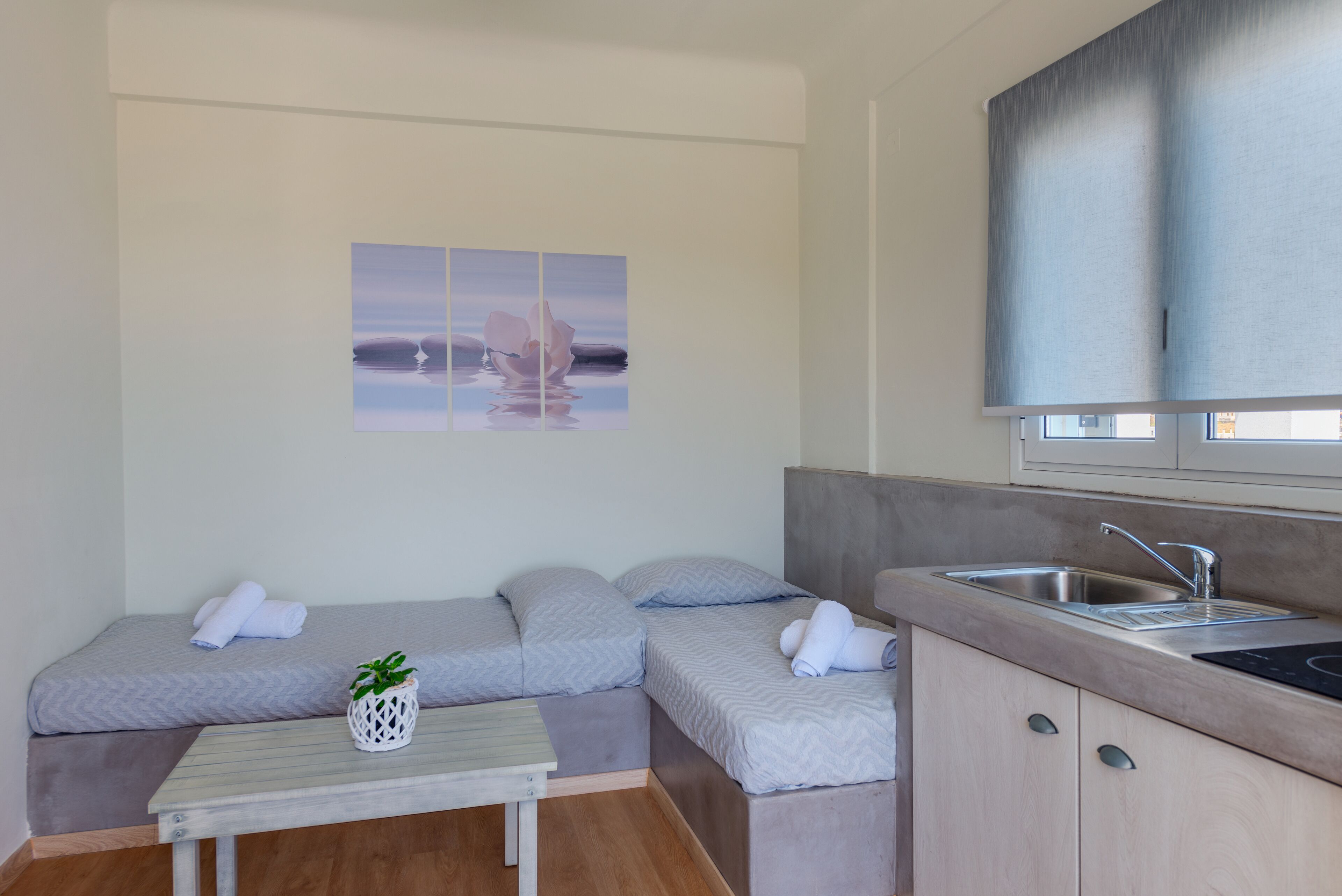 Una habitación compacta con kitchenette, una pequeña mesa de comedor y un sofá cama.