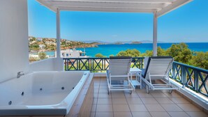 A balcony with a hot tub, two lounge chairs, and a view of the sea and hills. - Aegean Paradiso Vacation Club Adults Only (Syros)