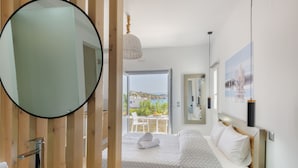 A modern bedroom with a large bed, a round mirror, and a view of the outdoors. - Aegean Paradiso Vacation Club Adults Only (Syros)