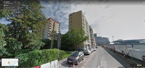 Straßenansicht mit einem Gebäude, auf dem '106 Chmielna' in Warschau steht. Es zeigt eine mehrstöckige Struktur mit Balkonen, parkenden Autos und Grünflächen.