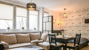 A modern living room with a sofa, a glass coffee table, and a dining area with chairs and a table. - Chmielna Superior (Warsaw)