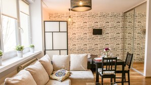A modern living room with a sofa, a dining table with chairs, and a patterned wallpaper. - Chmielna Superior (Warsaw)