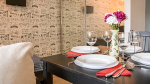 A dining table set with white plates, red napkins, and a vase with flowers. - Chmielna Superior (Warsaw)