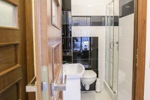Ein modernes Badezimmer mit Duschkabine aus Glas, einem weißen Waschbecken und einer Toilette.