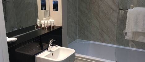 A modern bathroom with a white toilet, a sink, a bathtub, and a glass-enclosed shower.