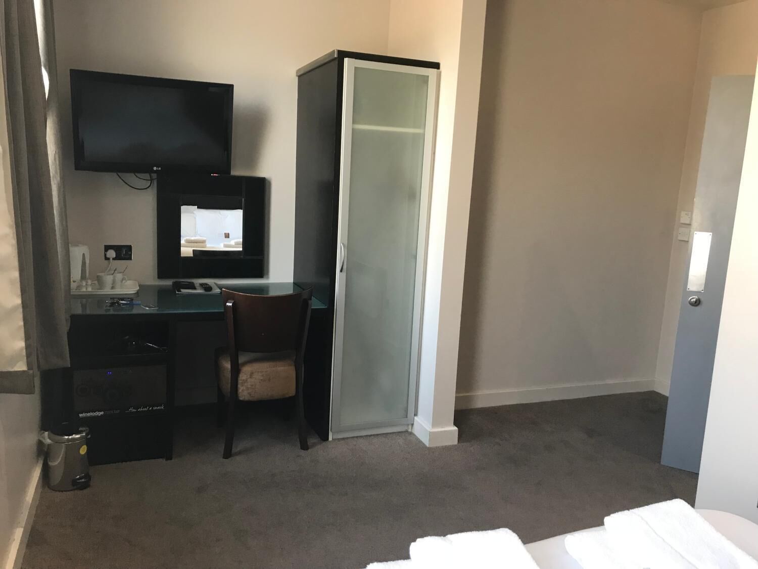 Een hotelkamer met een bureau, stoel, televisie en een kledingkast.
