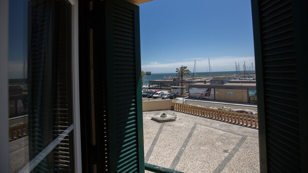 A view from a balcony with a clear sky, a parking area, and a distant shoreline. - HI Oeiras - Pousada de Juventude - Hostel (Oeiras)