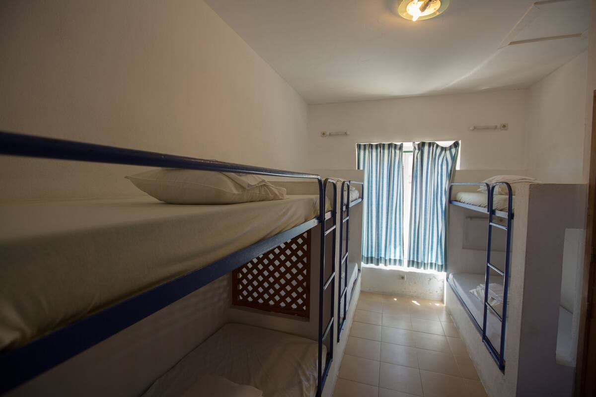 A bunk bed room with a window and curtains.