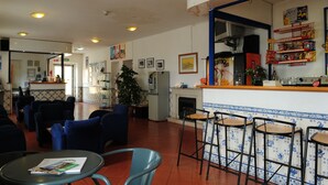 A restaurant with bar stools, a counter with snacks, and a fireplace. - HI Oeiras - Pousada de Juventude - Hostel (Oeiras)