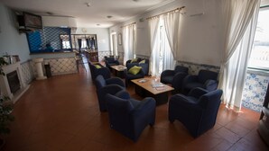 A spacious room with a kitchen area, a dining table with chairs, and a seating area with sofas and a coffee table. - HI Oeiras - Pousada de Juventude - Hostel (Oeiras)