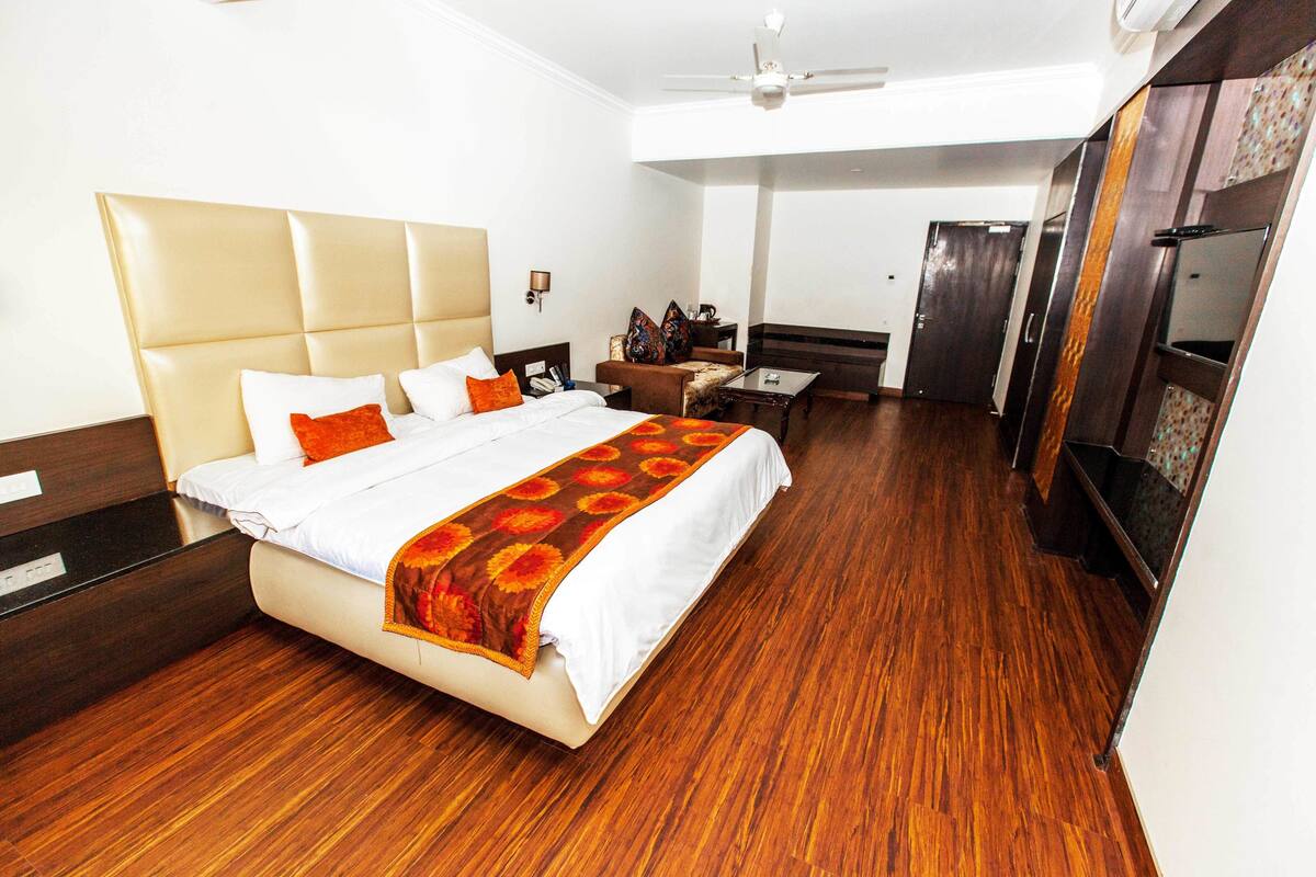 A hotel room with a large bed, a desk, and a wardrobe.