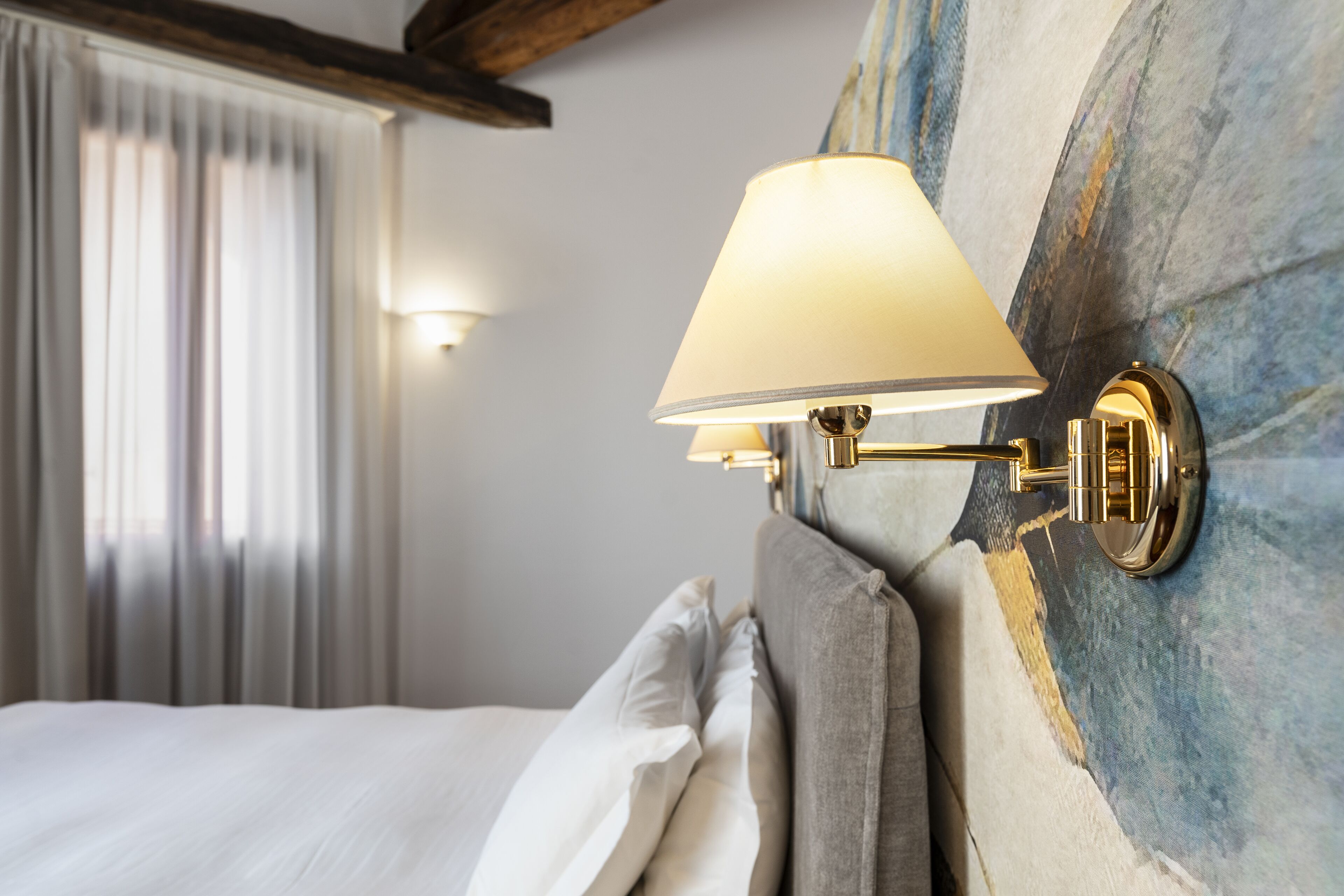 Una cama bien hecha con sábanas blancas y un cabecero con diseño texturizado en azul y blanco.