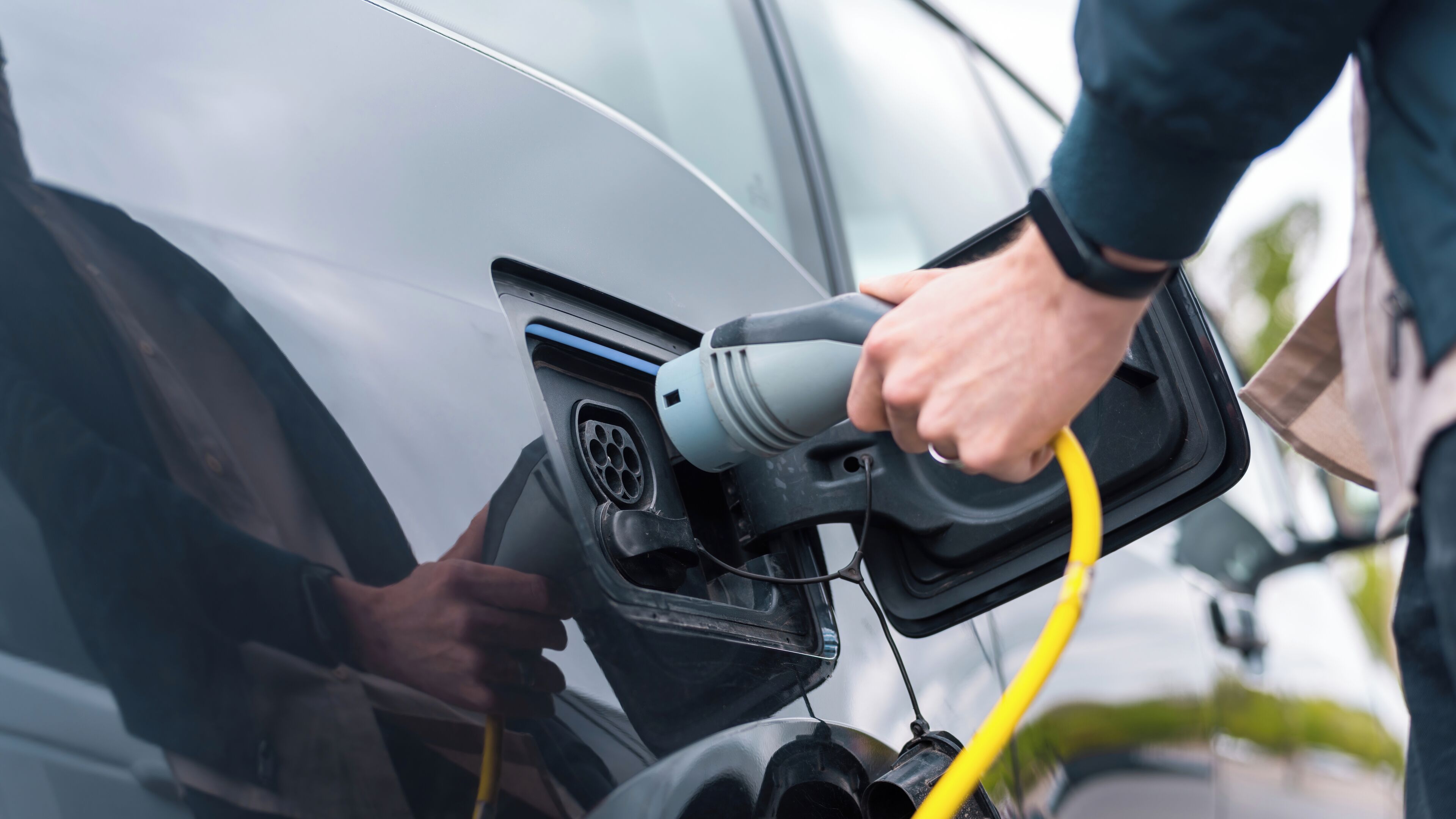 Una persona conectando un vehículo eléctrico a una estación de carga.