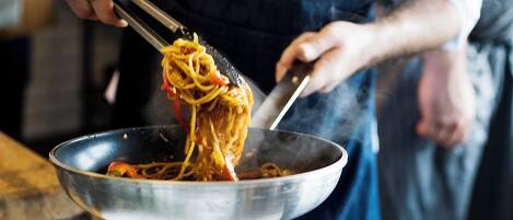A person cooking spaghetti in a pan.
