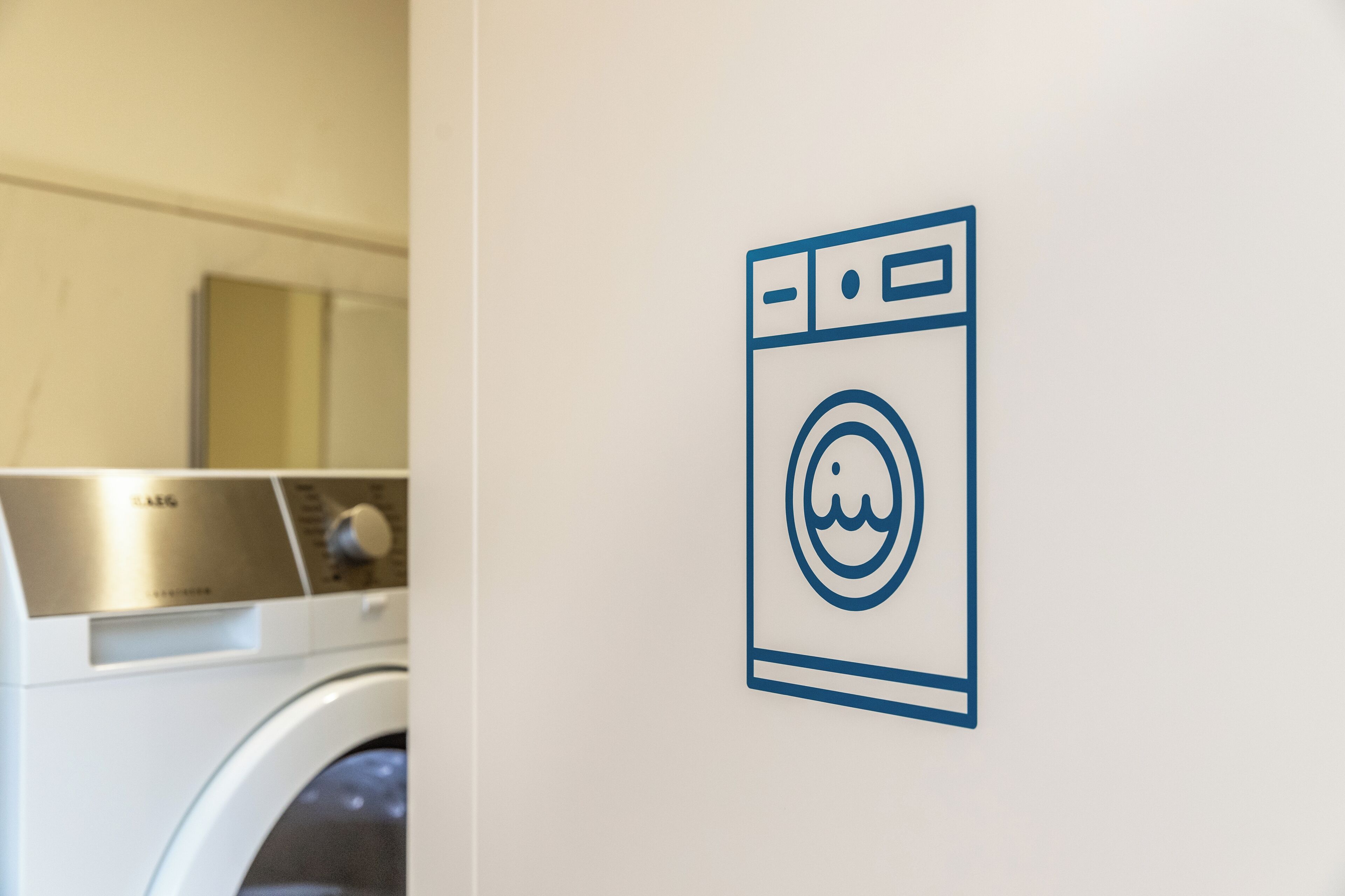 Een pictogram aan de muur van een wasmachine, wat duidt op een wasserette.