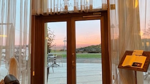 A hotel entrance with a wooden door, a view of the outdoors, and a table with a menu. - Hotel Alle Acque (Lonigo)